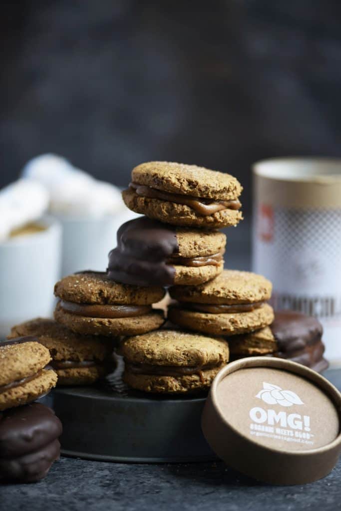 Stack of hot cocoa gingerbread sandwich cookies dipped in chocolate on dark background