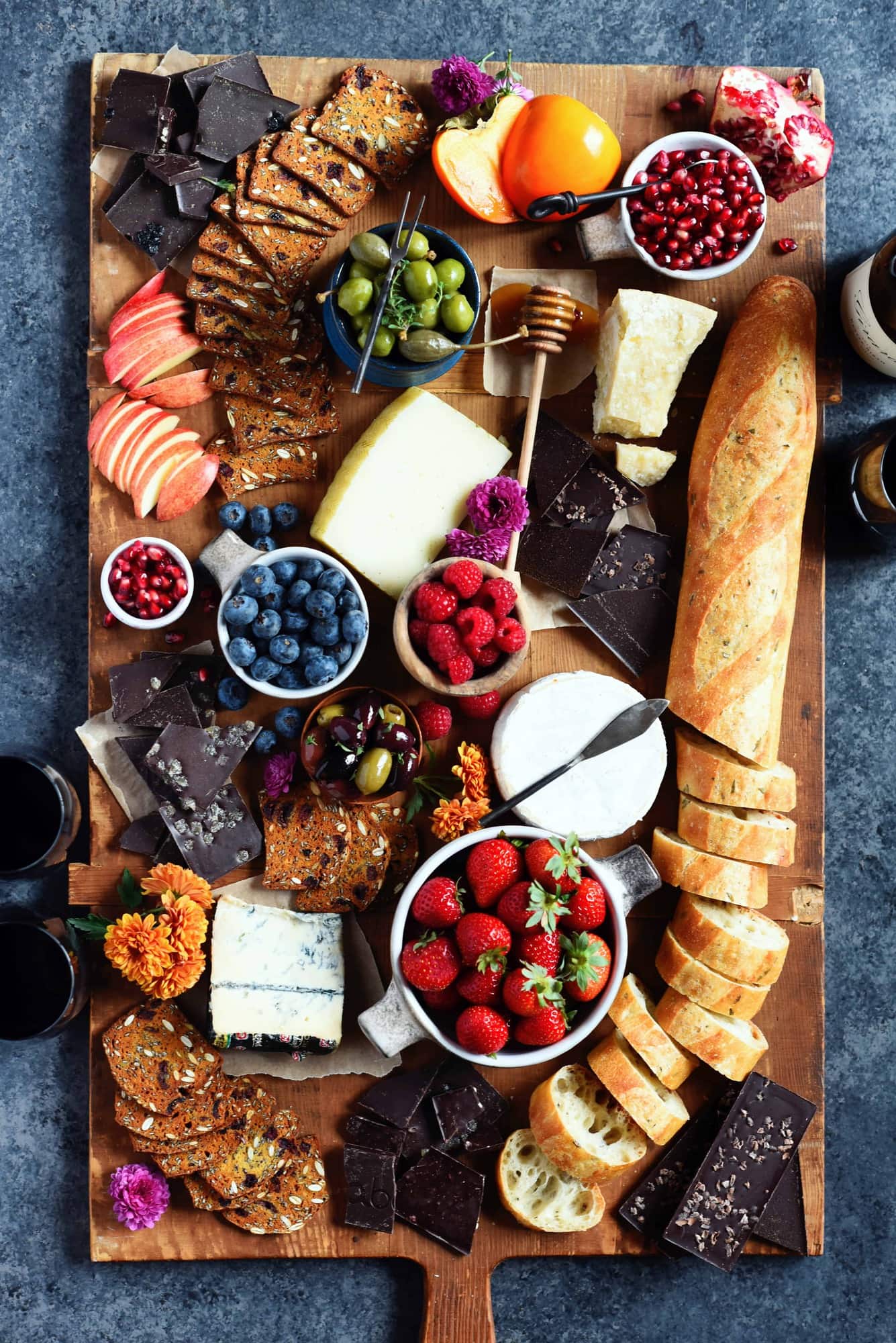 Overhead of cheese board with fresh fruit, bread and crackers