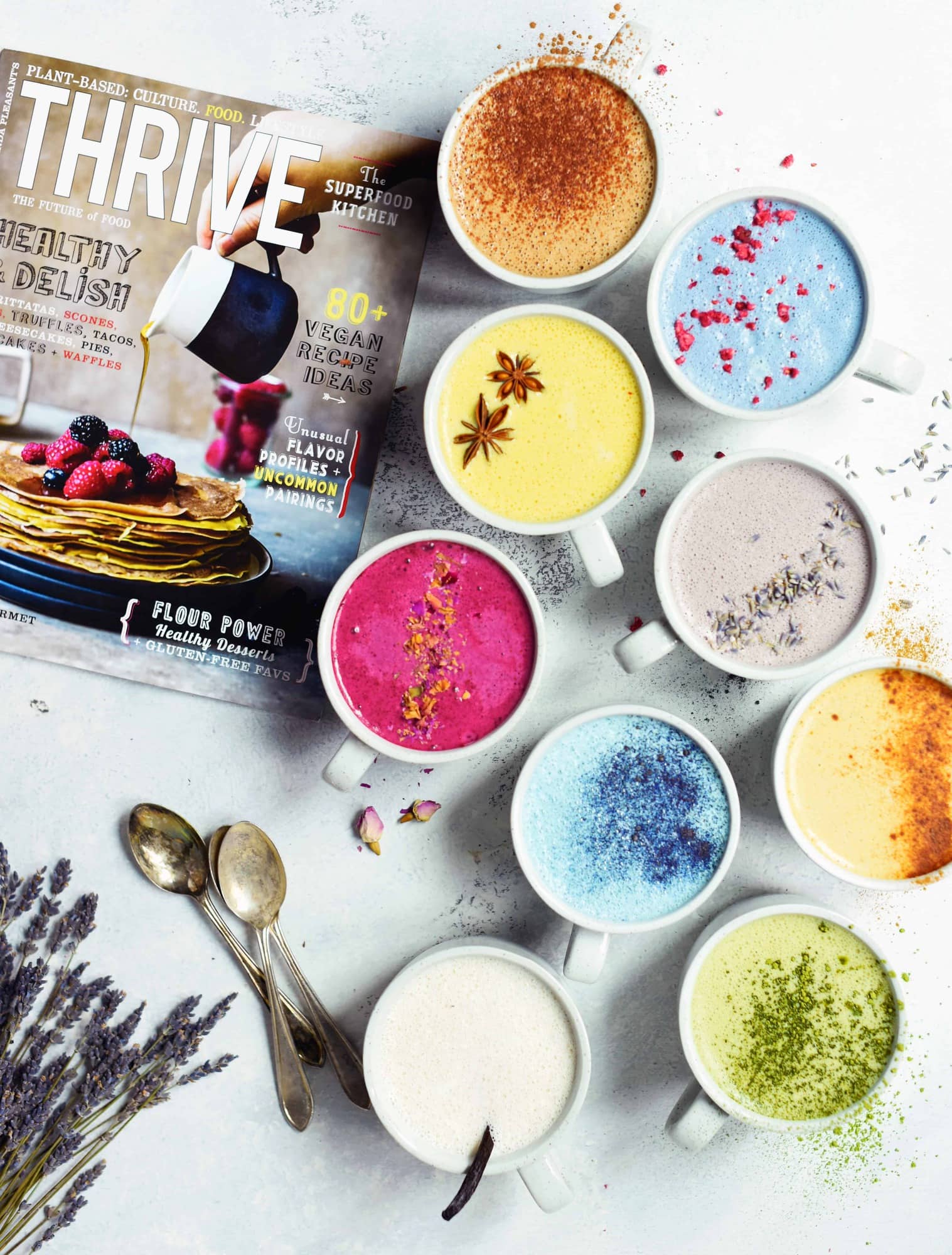 Overhead of naturally colored lattes in white mugs on white background next to Thrive magazine