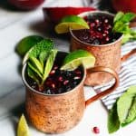 Side view of pomegranate moscow mule garnished with mint and lime