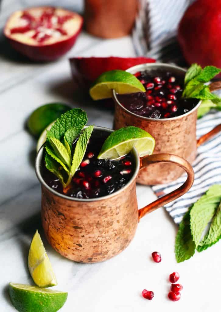 Side view of pomegranate moscow mule garnished with mint and lime