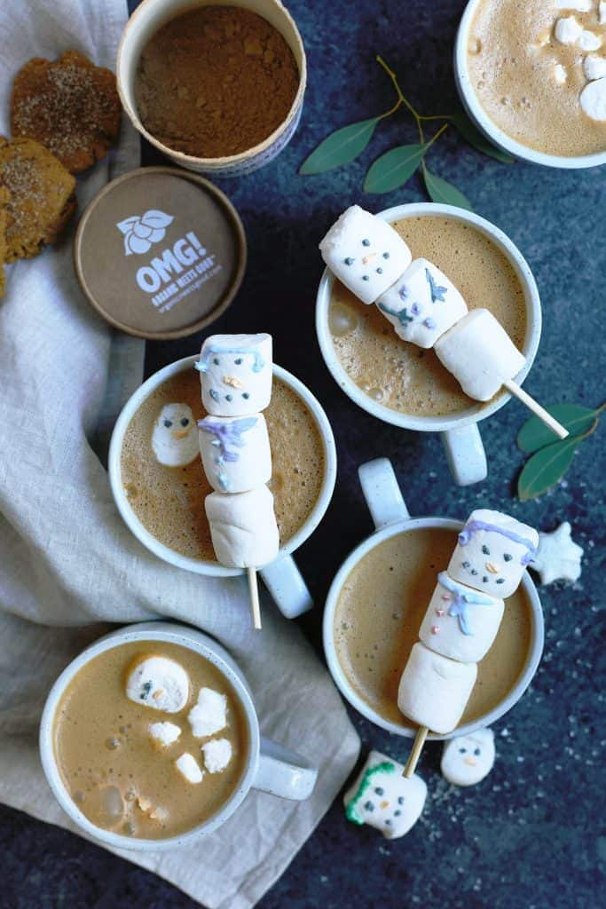 Overhead of mugs of hot cocoa topped with marshmallow snowmen