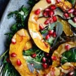 Close up Overhead of squash salad with pomegranate and tahini dressing on a silver antique platter