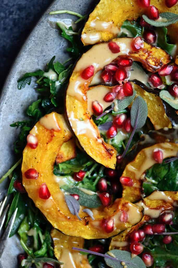 Close up Overhead of squash salad with pomegranate and tahini dressing on a silver antique platter