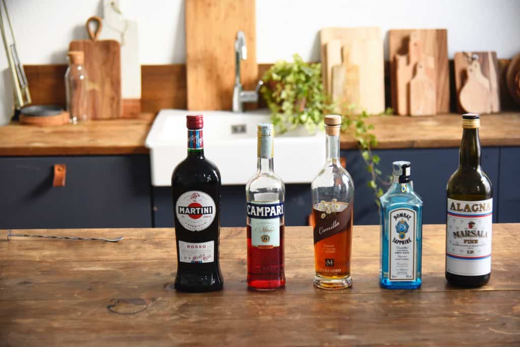 Bottles of alcohol on a wood table in a bright, rustic kitchen