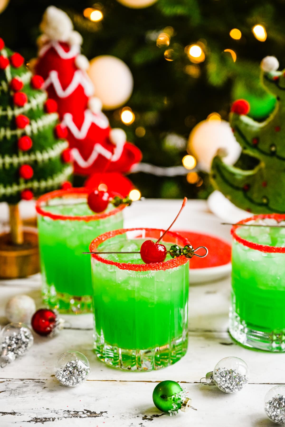 Finished grinch cocktails with cherry garnish and red rim.