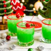 Finished grinch cocktail in glasses with red sprinkle rim.