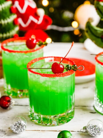 Finished grinch cocktail in glasses with red sprinkle rim.
