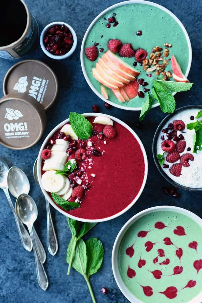 Overhead of three holiday smoothie bowls with bananas and fresh berries