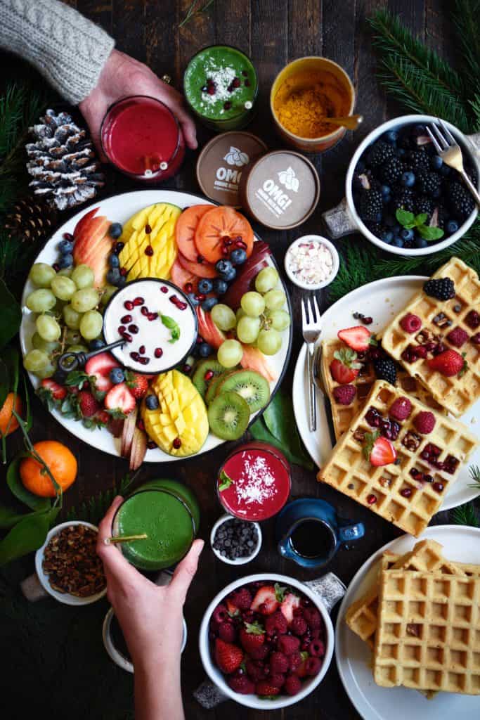Overhead of spread with waffles and fruit on rustic wood background