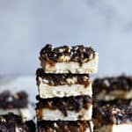 Stack of pecan caramel shortbread bars on a white background