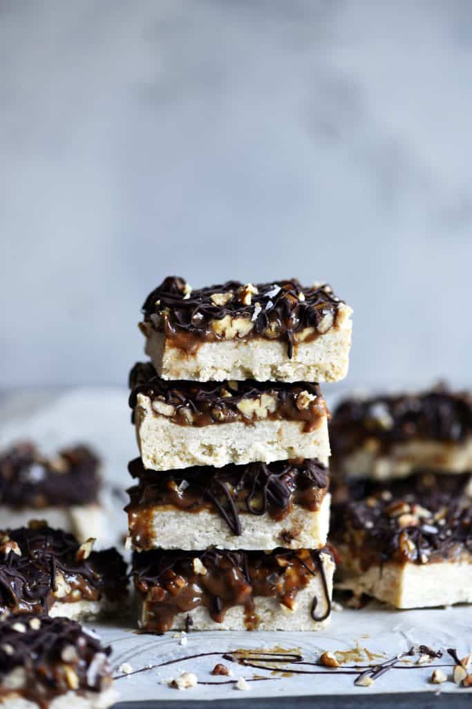 Stack of pecan caramel shortbread bars on a white background
