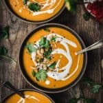 Overhead of coconut curry squash soup garnished with lime, cilantro and coconut milk