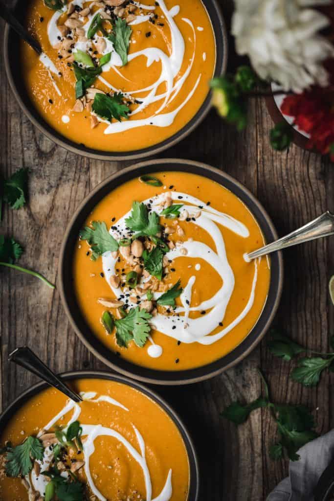 Overhead of coconut curry squash soup garnished with lime, cilantro and coconut milk