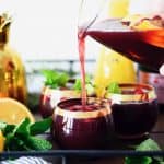 Pouring holiday sparkling punch into glasses on bar cart