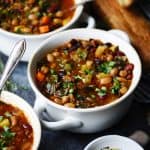 Side view of five bean vegetable soup in a white bowl