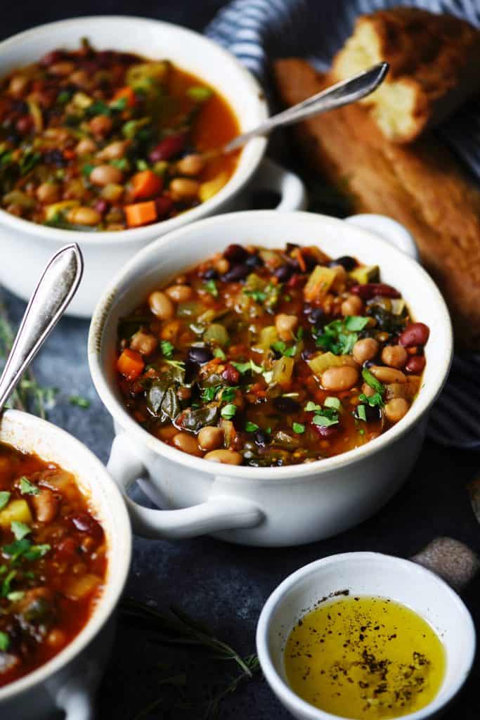 Side view of five bean vegetable soup in a white bowl