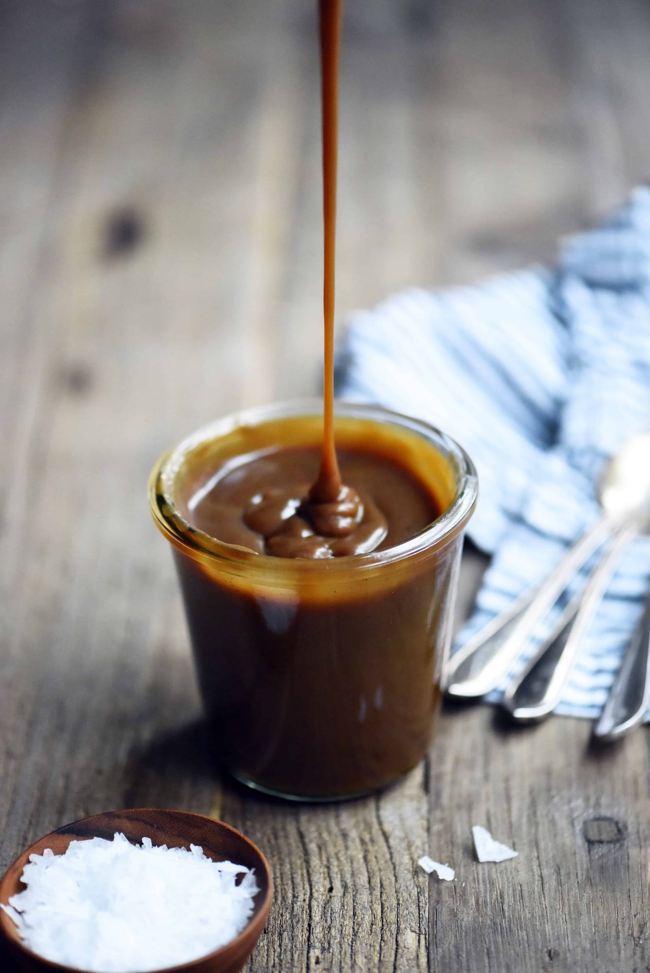 45 degree angle of salted caramel sauce being drizzled into a glass jar