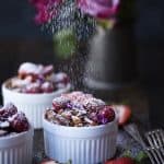 Dusting powdered sugar onto french toast bake in a small white ramekin