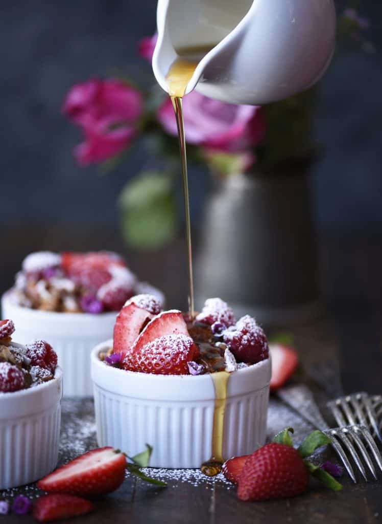 Pouring maple syrup onto french toast bake in a small white ramekin