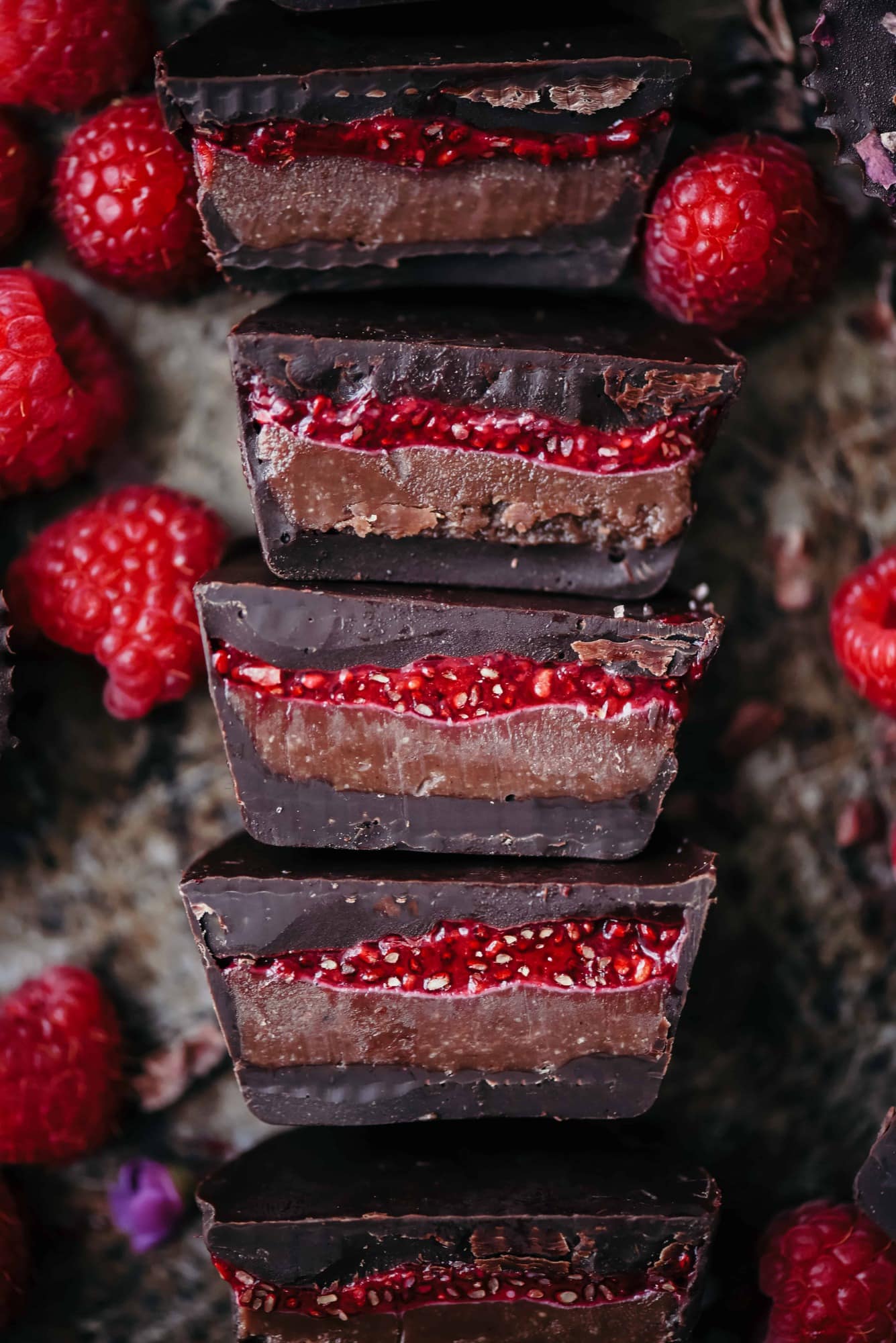 Overhead of chocolate cashew butter cups with raspberry chia jam sliced in half on an antique sheet pan with fresh raspberries