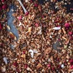 Overhead of chocolate hazelnut raspberry granola on a sheet pan with a large spoon