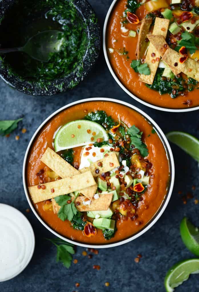 Overhead of fire roasted tomato soup with tortilla strips and avocado