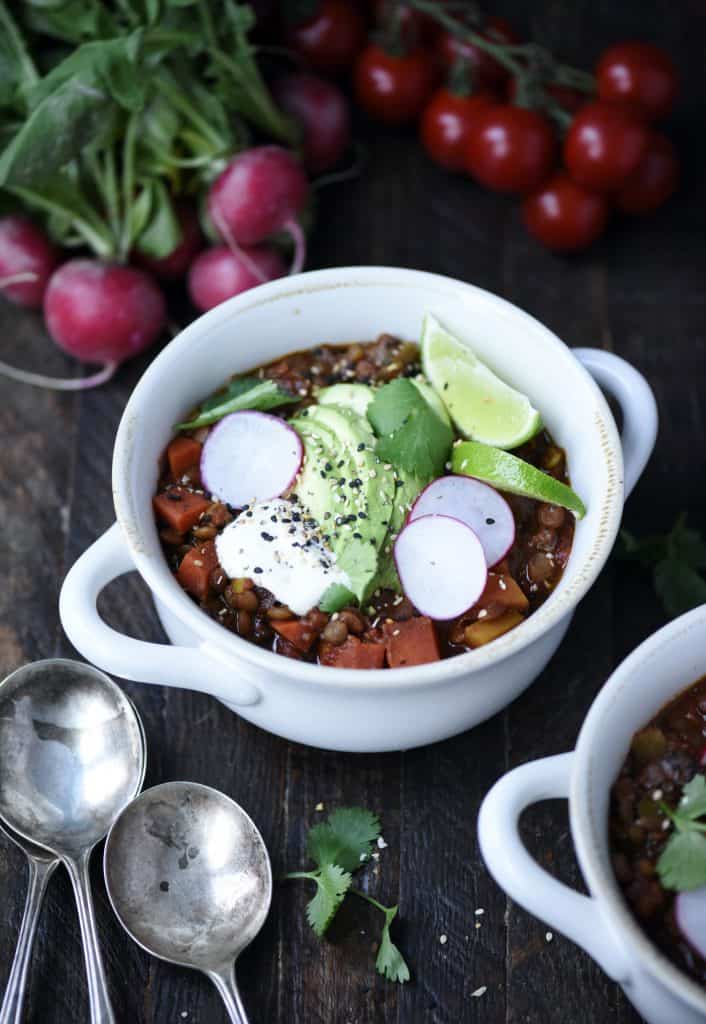 45 Degree Angle of vegan chili in a white pot with radishes and toppings
