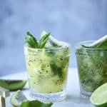 Side view of kiwi caipirinha garnished with fresh mint on a marble serving tray