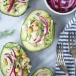 Overhead of avocados stuffed with chickpea salad and pickled red onions on a white background