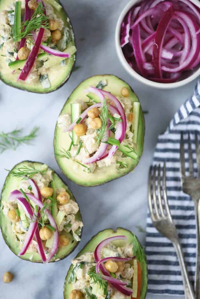 Overhead of avocados stuffed with chickpea salad and pickled red onions on a white background