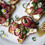 Close up Overhead of toast with ricotta and roasted strawberries on a white plate