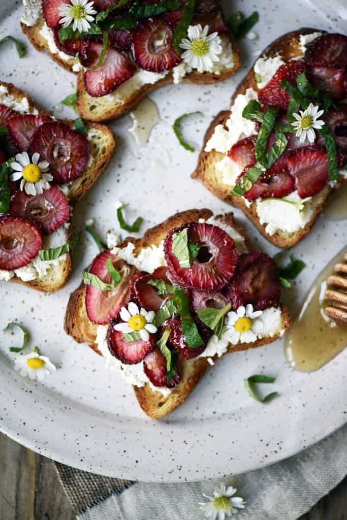 Close up Overhead of toast with ricotta and roasted strawberries on a white plate