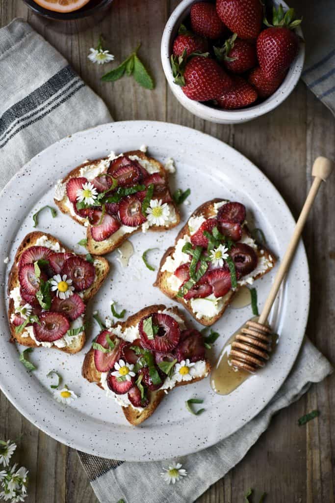 Overhead of toast with ricotta and roasted strawberries on a white plate