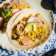 Tacos on a plate garnished with avocado.