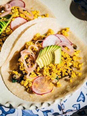 Tacos on a plate garnished with avocado.