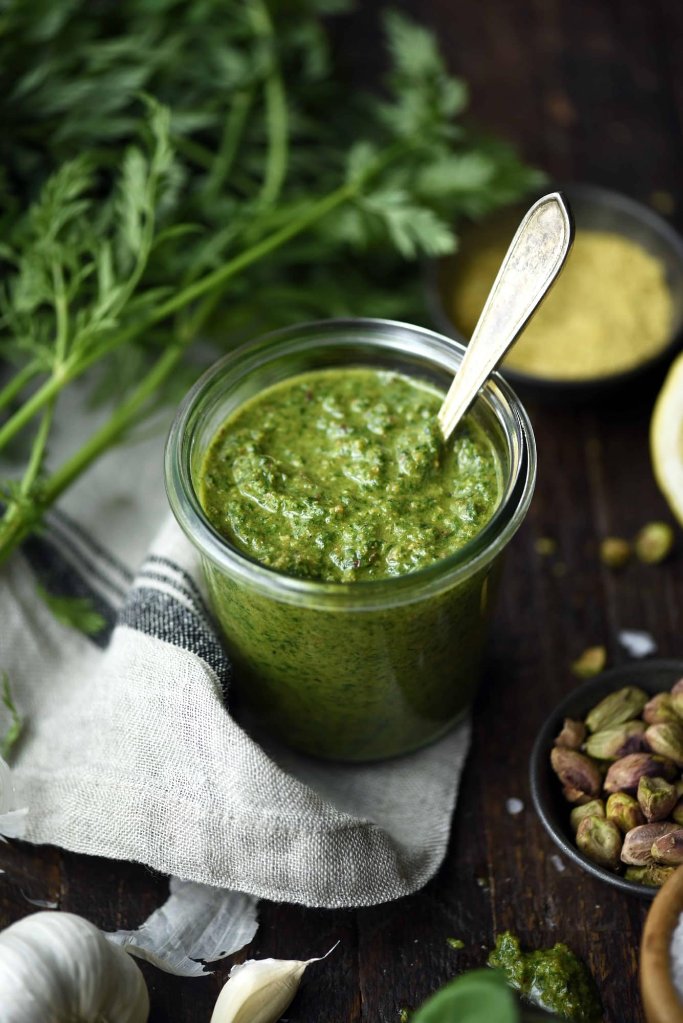 Side view of carrot top pesto in a glass jar