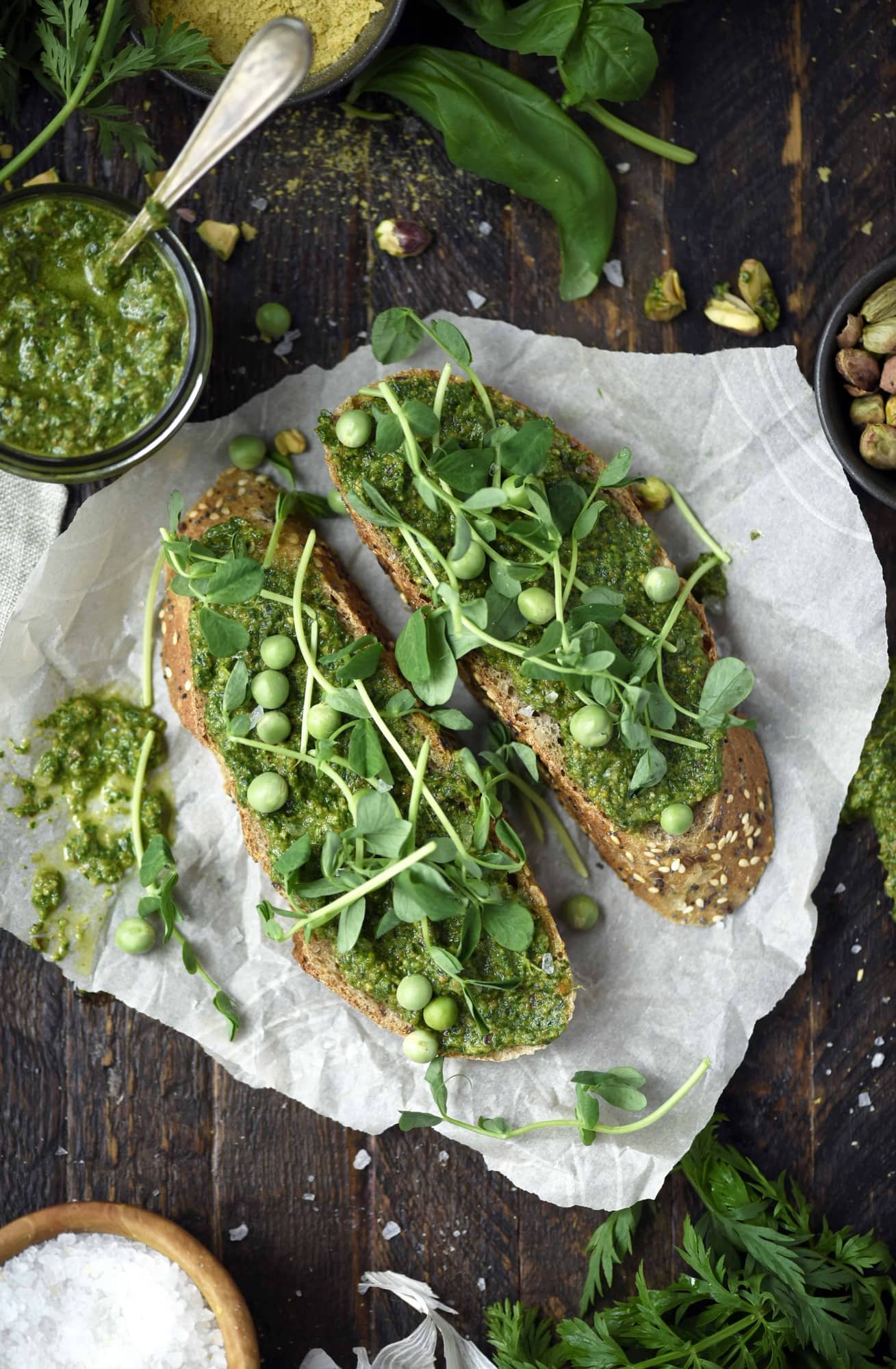 Overhead of two pieces of toast topped with vegan pesto, peas and greens
