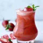 Side view of strawberry rhubarb daiquiri in a curved glass garnished with rhubarb ribbons