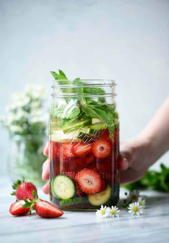 Hang grabbing large glass jar of strawberry cucumber mint infused water