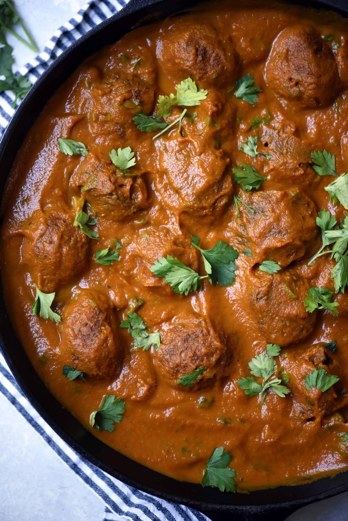 Close up overhead of vegan juice pulp meatballs in sauce in a cast iron skillet