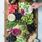 Overhead of snack platter on huge wood board with pink, purple and green vegetables