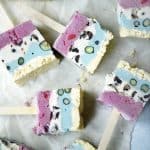 Overhead of red white and blue ice cream pops laying on their sides on parchment paper