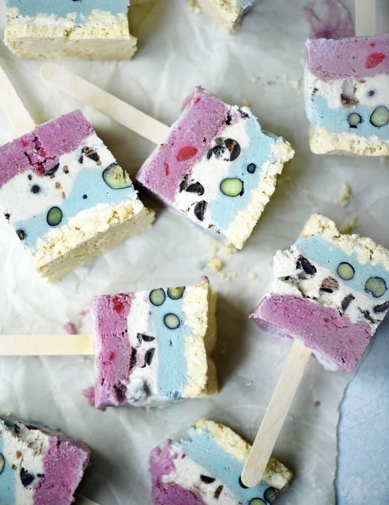 Overhead of red white and blue ice cream pops laying on their sides on parchment paper