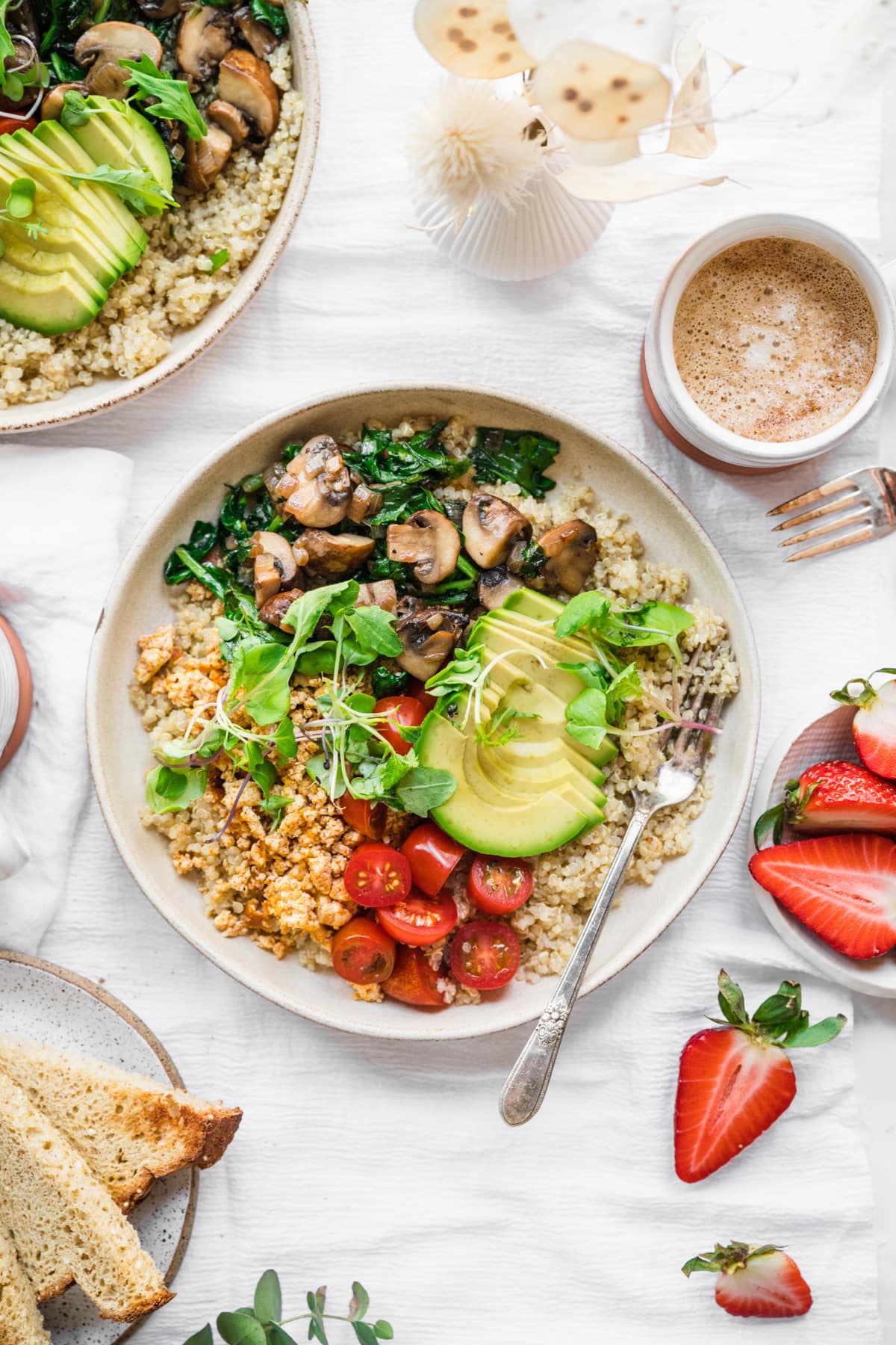 overhead view of vegan savory quinoa breakfast bowl with tofu, avocado and mushrooms. 