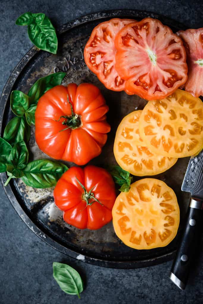 Overhead of beautiful red and yellow heirloom tomatoes with fresh basil