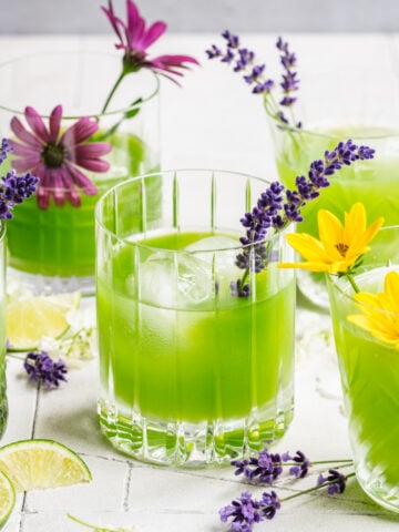 Green cocktail in cocktail glasses garnished with flowers.