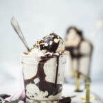 Side view of cold brew chai vegan ice cream in a glass with chocolate sauce on white background