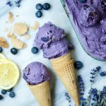 Blueberry Lavender Ice Cream in 2 waffle cones on a marble background with fresh lemon slices
