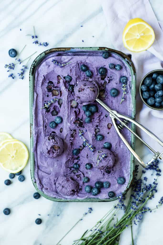 Overhead of blueberry lavender ice cream in an antique blue sheet pan with ice cream scoop